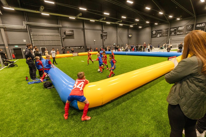 En inomhusplan för fotboll. Barn som springer på planen.