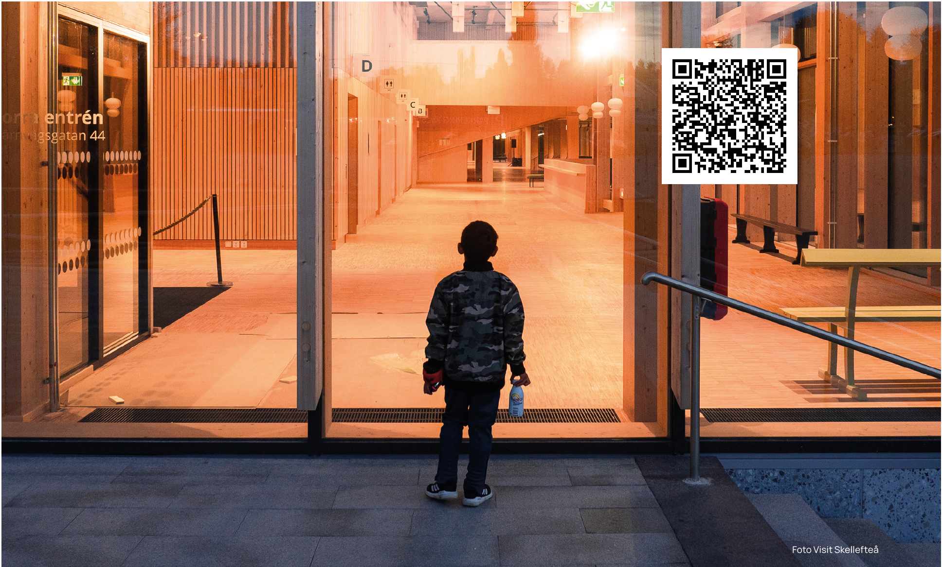 Ett barn är på väg in genom stora glasdörrar, till en galleria