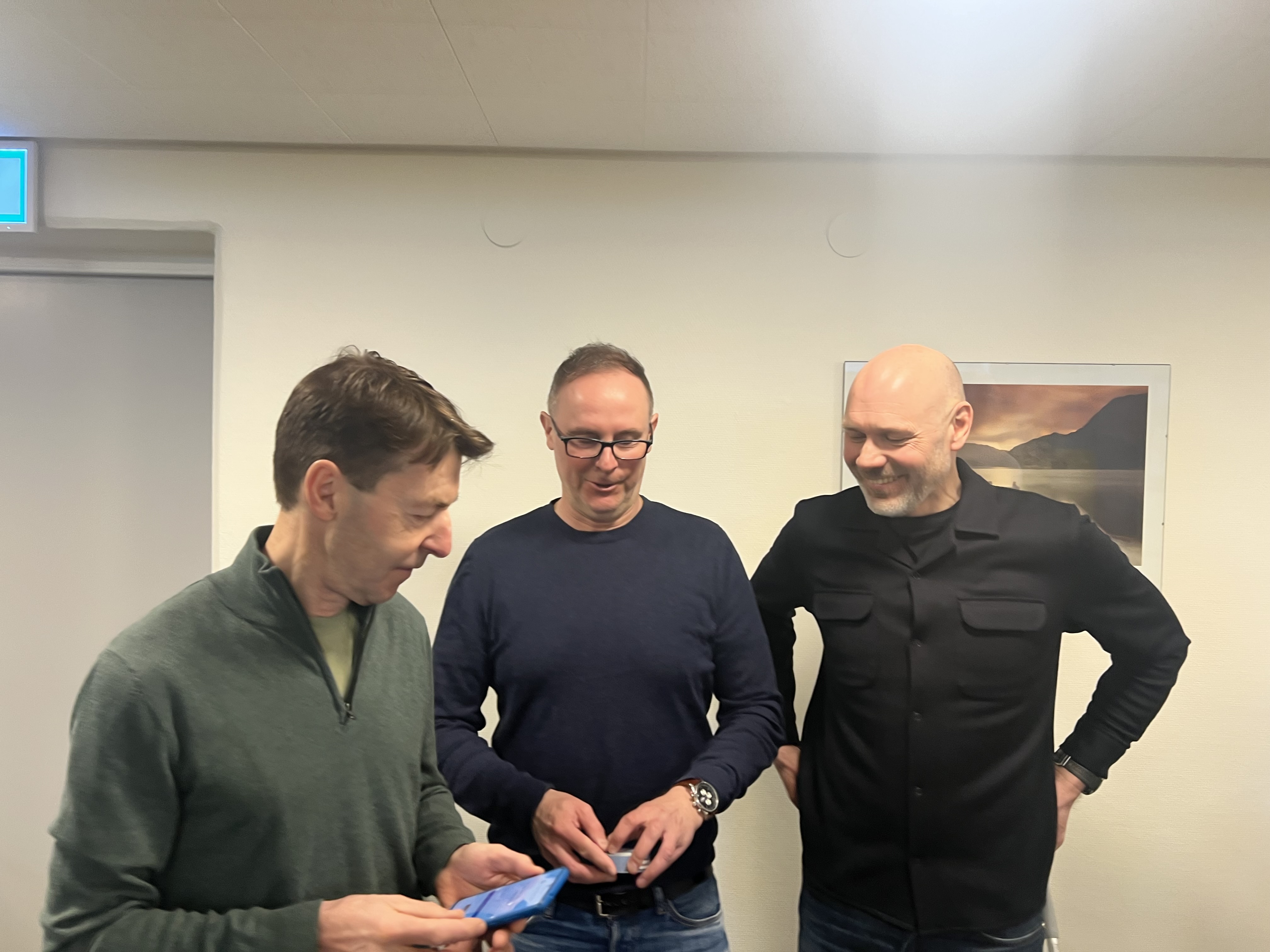 Tre personer tittar på en mobiltelefon