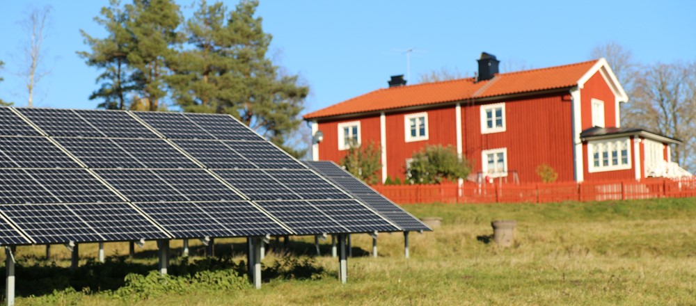 Solceller framför ett rött hus