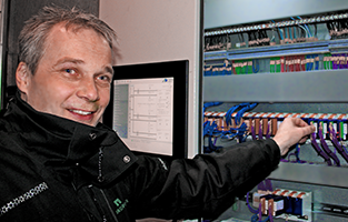 En glad man som står framför ett snabbsäkringsskåp och ska dra ner en av säkringarna