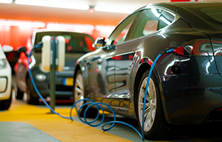 Två mörka bilar som laddar på en laddplats. 