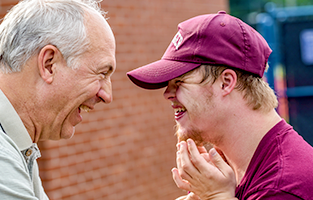 En äldre man och en person med funktionsvariation skaratar mot varandra i profil.