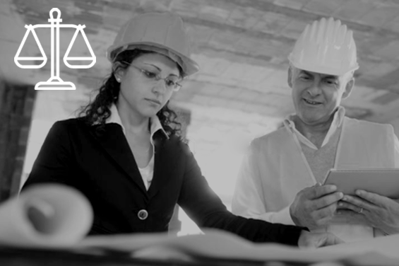 En man och kvinna med hjälmar i på ett byggkontor kvinnan står och tittar på en ritning. Bilden är svartvit