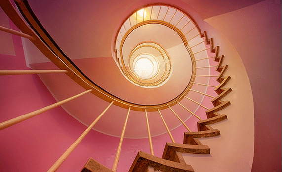 Rosa bild på en snurrtrappa. Bilden är tagen nedifrån och upp